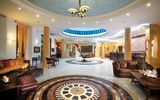 Prächtige Hotellobby mit kunstvoll gemustertem Marmorboden, eleganten Säulen und stilvollen Sitzbereichen – die einladende Atmosphäre wird durch eine imposante Kuppel mit Oberlicht und luxuriöse Details unterstrichen.