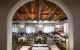 Traditionell eingerichtetes Restaurant mit rustikalem Charme, gemütlichen Holzmöbeln, weiß eingedeckten Tischen und einer offenen Holzbalkendecke – warme Beleuchtung sorgt für ein einladendes Ambiente.