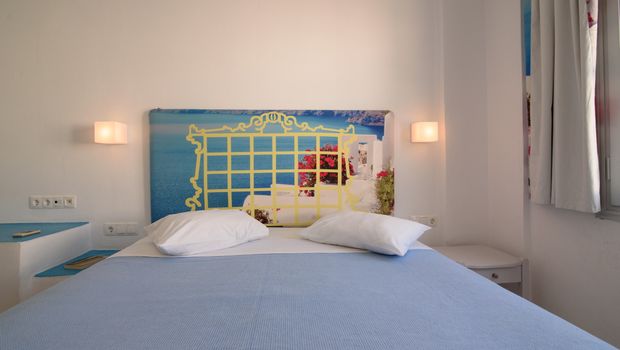 Helles Zimmer mit Doppelbett, dekorativem Fotokopfteil mit Meerblick-Motiv und mediterraner Atmosphäre – ideal für entspannte Urlaubstage.