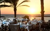 Stimmungsvoll gedeckte Tische auf der Restaurantterrasse mit Blick auf das Meer und einen traumhaften Sonnenuntergang.