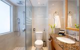 Modernes Badezimmer mit ebenerdiger Dusche, WC und großem Waschtisch mit Granitplatte.