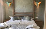 Modern eingerichtetes Doppelzimmer mit zwei zusammengestellten Einzelbetten, dekorativen Kissen und auffälligen Designer-Hängelampen – warme Holz- und Naturtöne sorgen für eine gemütliche Atmosphäre.