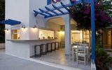 Gemütliche Außenterrasse mit Bar und Sitzgelegenheiten unter einem blauen Holzpergola, geschmückt mit blühender Bougainvillea – ideal für entspannte Abende in mediterranem Ambiente.