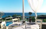Stilvoll gedeckter Tisch auf einer Terrasse mit traumhaftem Blick über das tiefblaue Meer – ideal für ein entspanntes Mittag- oder Abendessen mit mediterranem Flair.