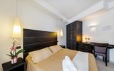 Modern eingerichtetes Doppelzimmer mit warmen Farbtönen, stilvollen Möbeln, Schreibtisch und frischer Orchidee – ideal für entspannte Urlaubstage mit Komfort.